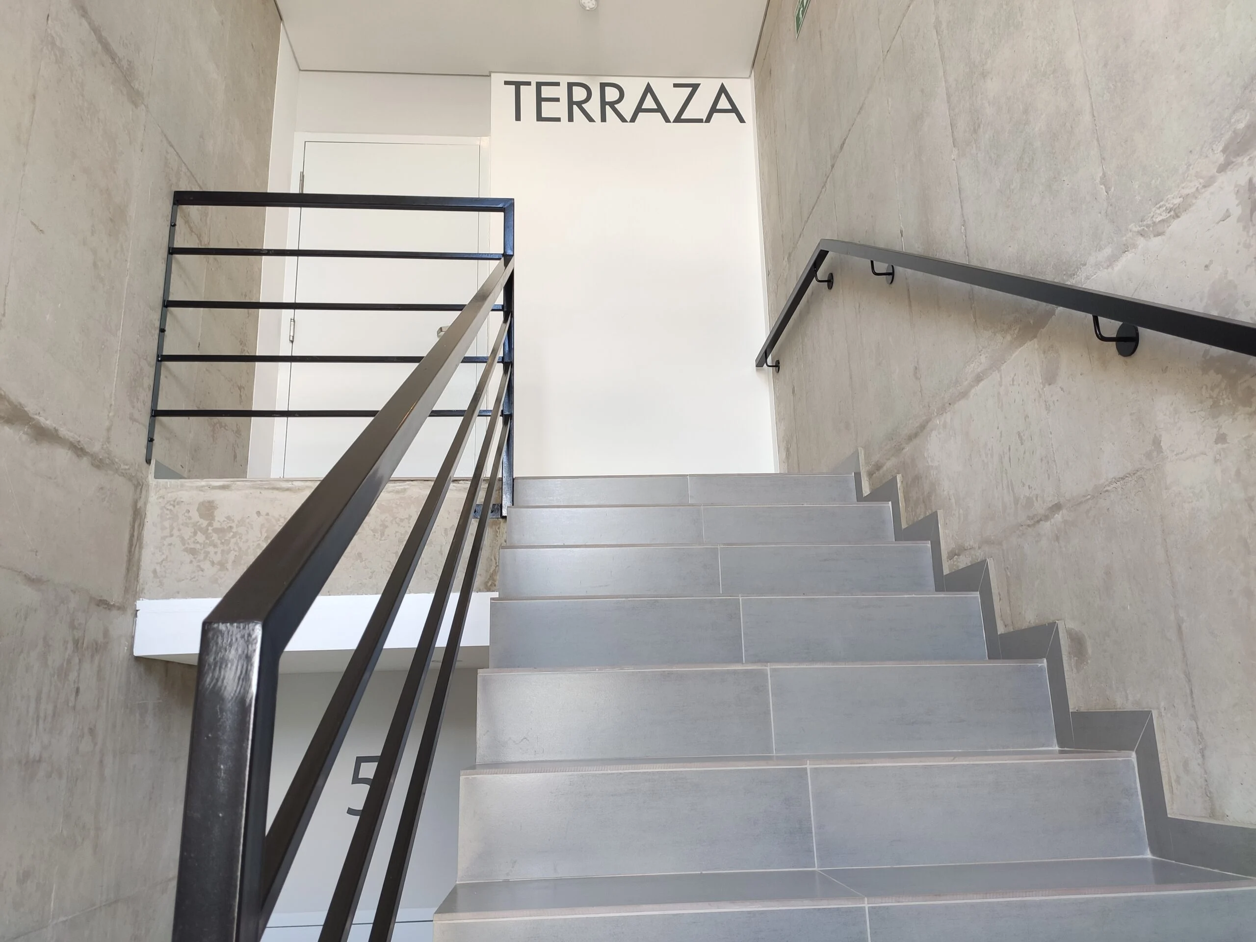 Baranda metálica de barrotes horizontales en escalera hacia terraza