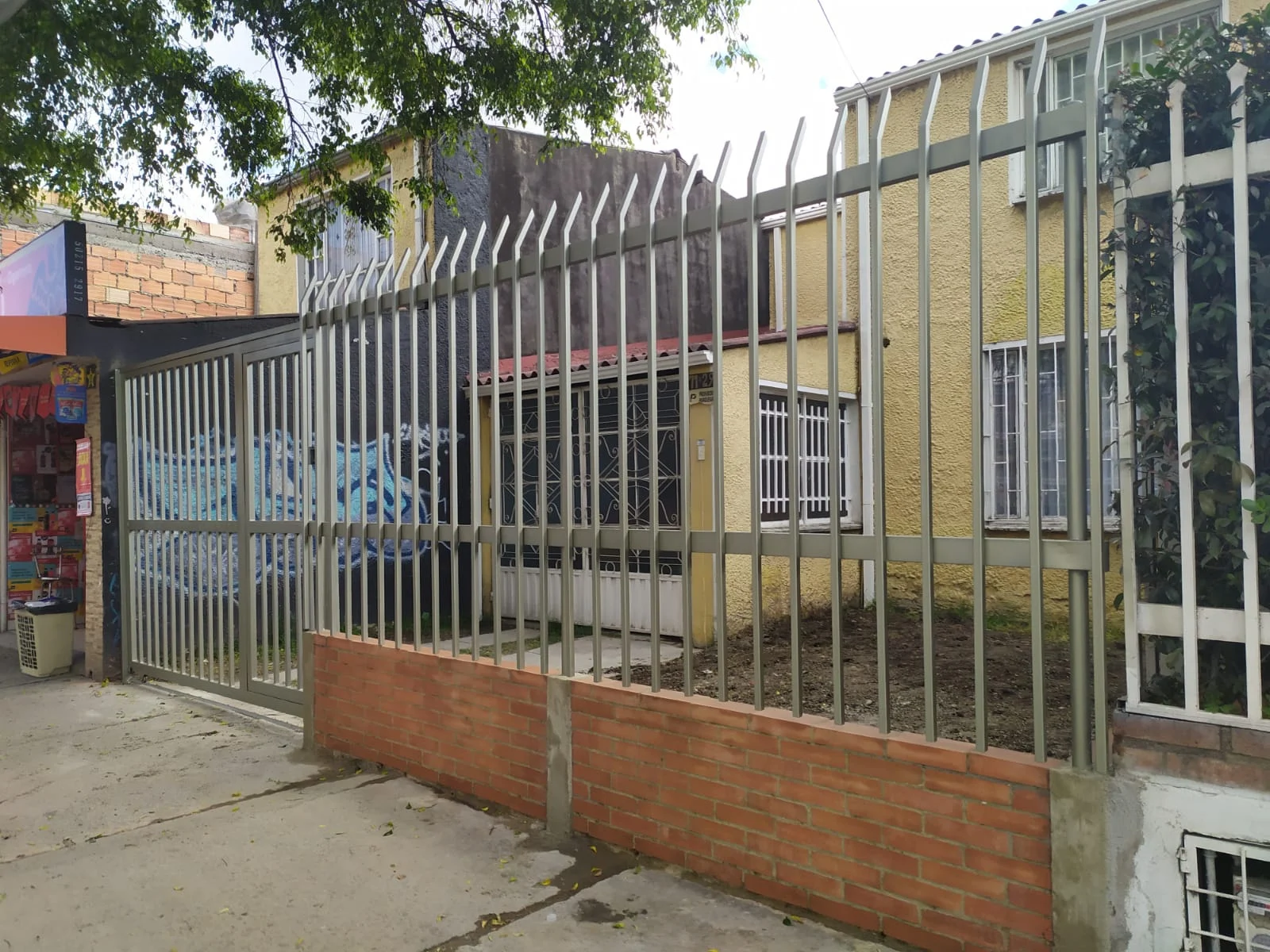 Cerramiento metálico perimetral sobre muro, con reja de barrotes altos