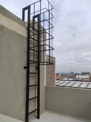 Escalera de metal negro en exterior, conectando una terraza con el techo de un edificio urbano