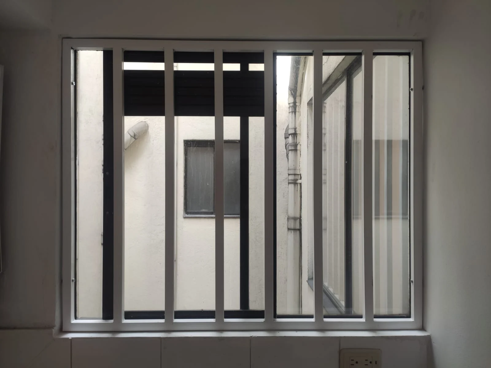 Reja metálica blanca de barrotes verticales en ventana de vivienda