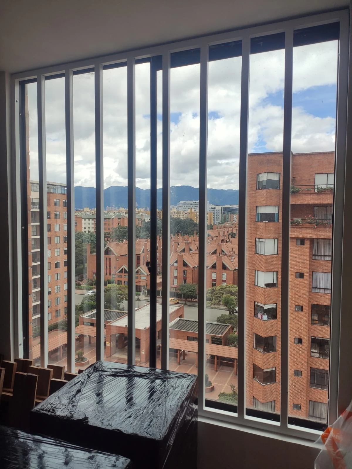 Reja metálica blanca en ventanal con vista a la ciudad