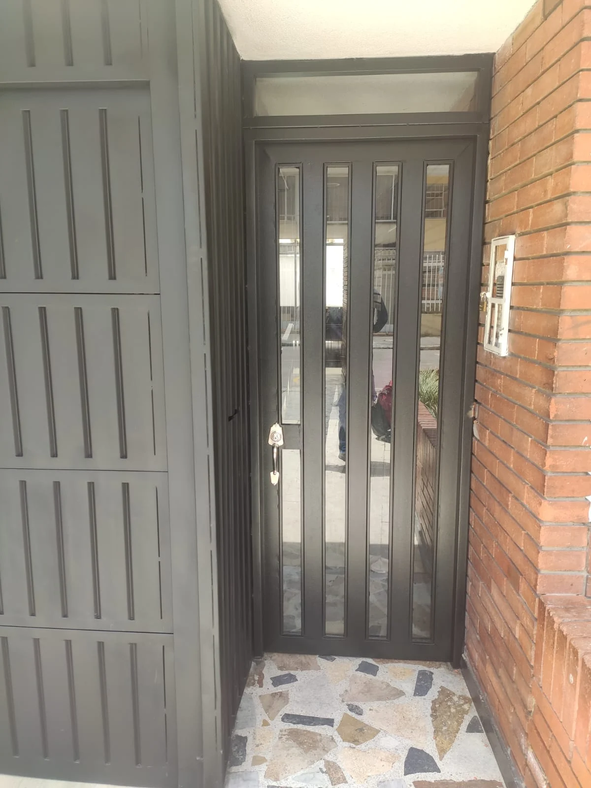 Portón metálico gris con puerta peatonal integrada