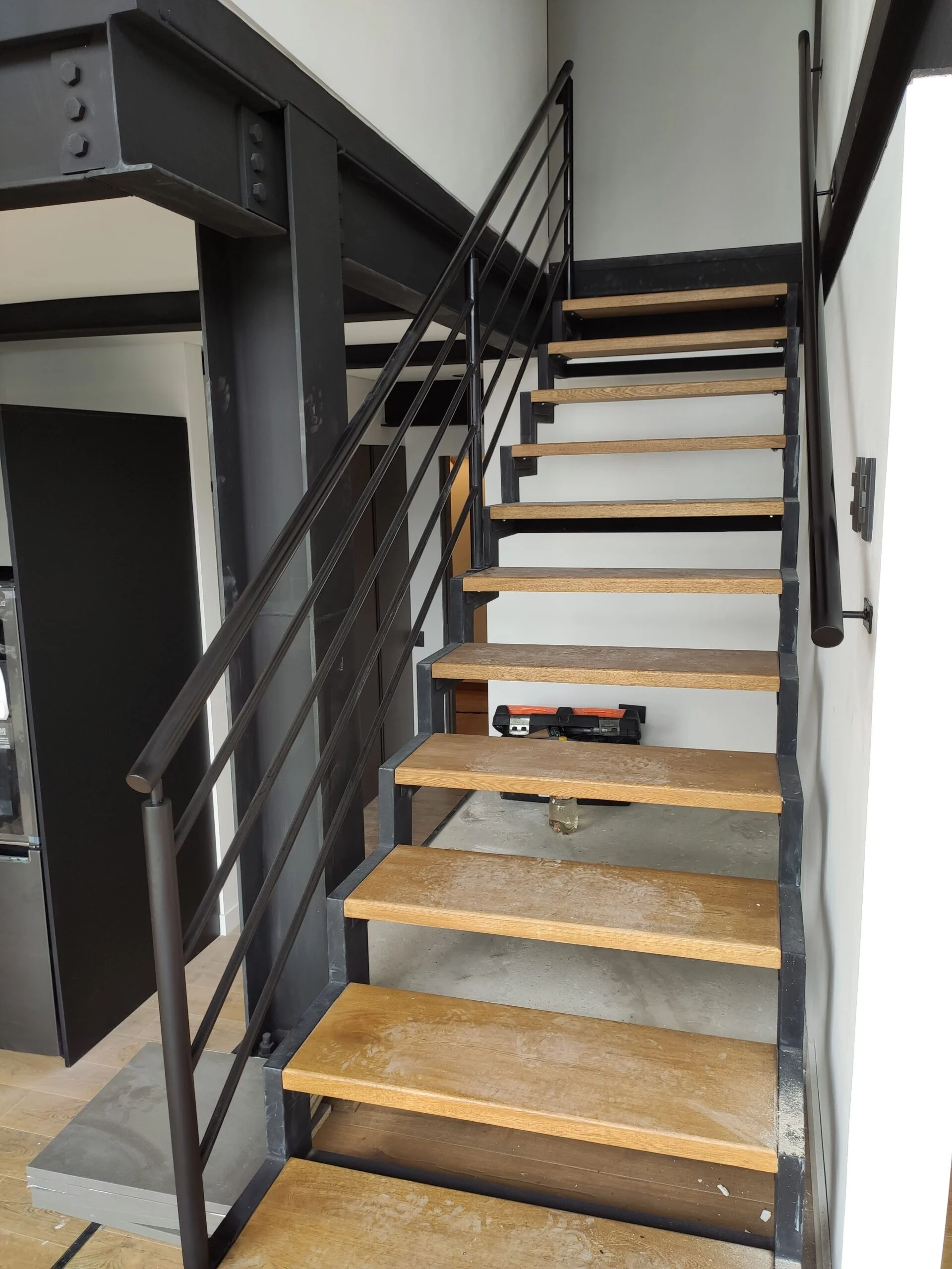 Escalera metálica con peldaños de madera y baranda de perfil negro