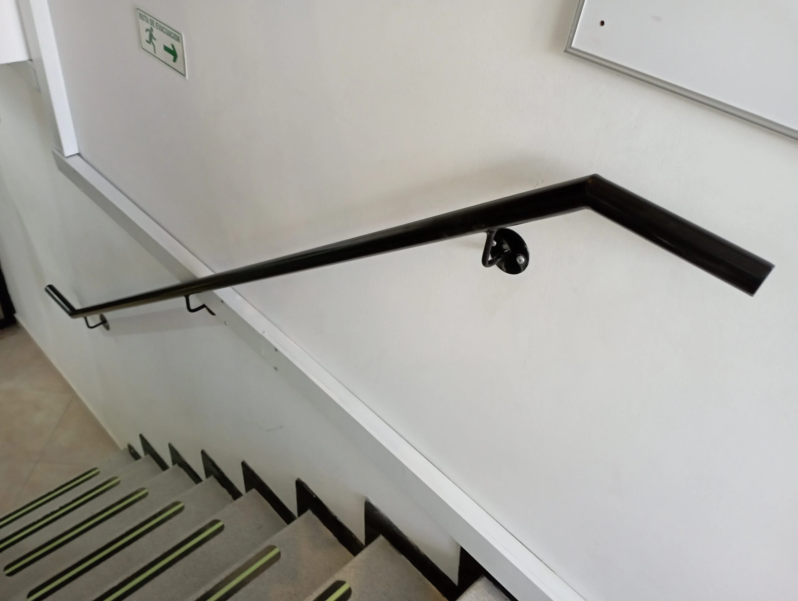 Pasamanos metálico negro de pared en escalera de edificio