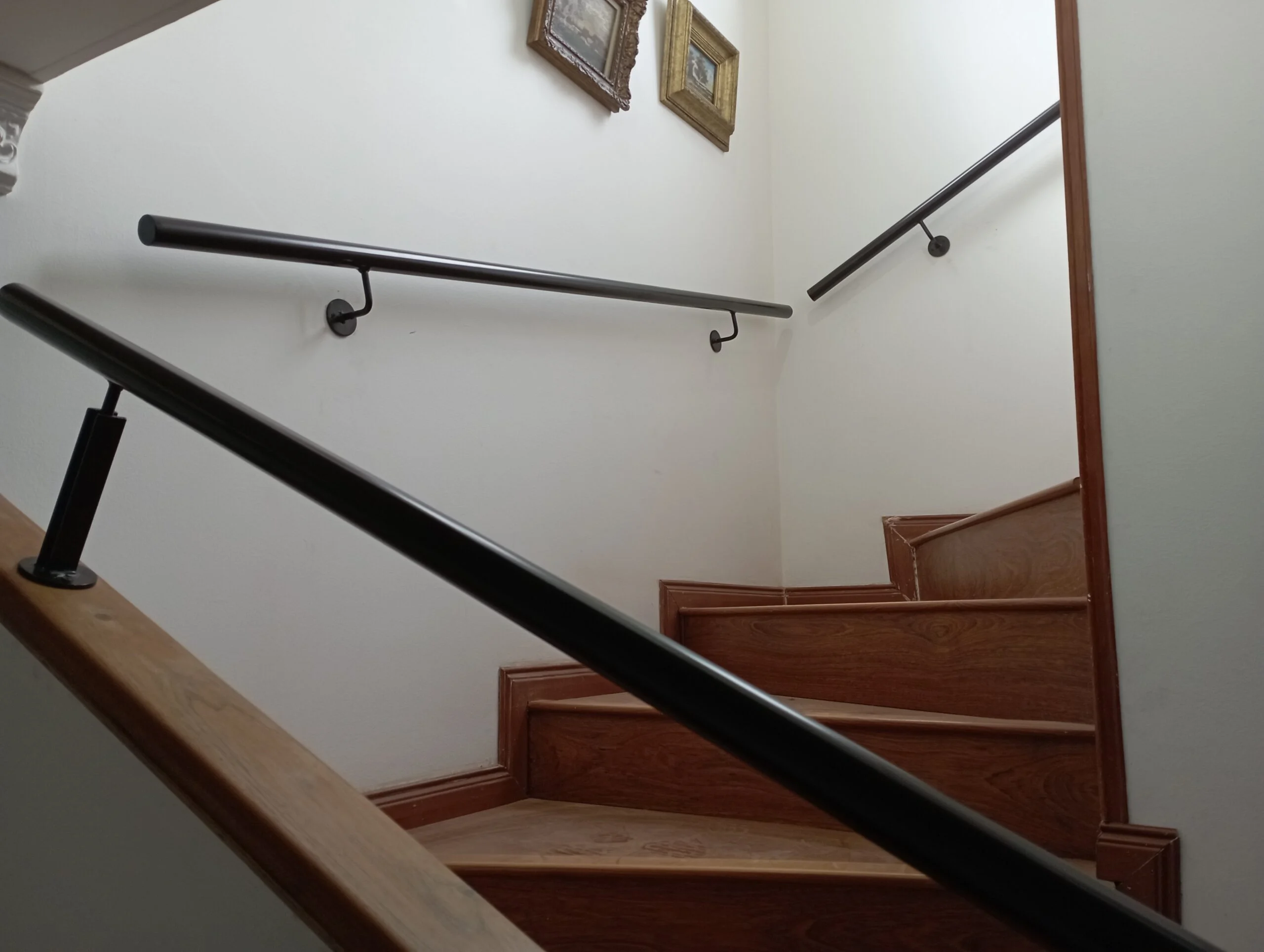 Pasamanos metálico negro de pared en escalera interior de vivienda