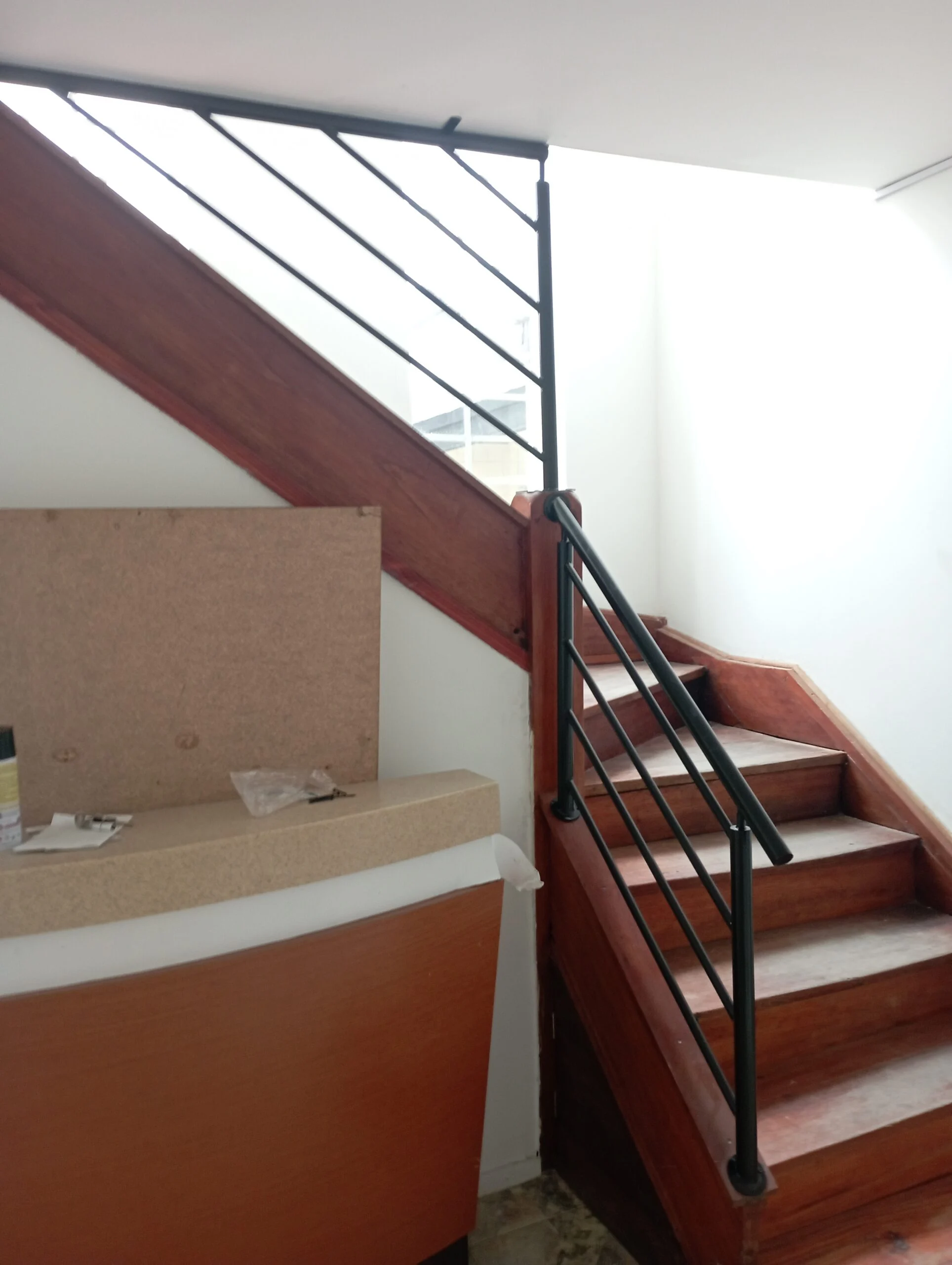 Baranda metálica negra en escalera interior con peldaños de madera