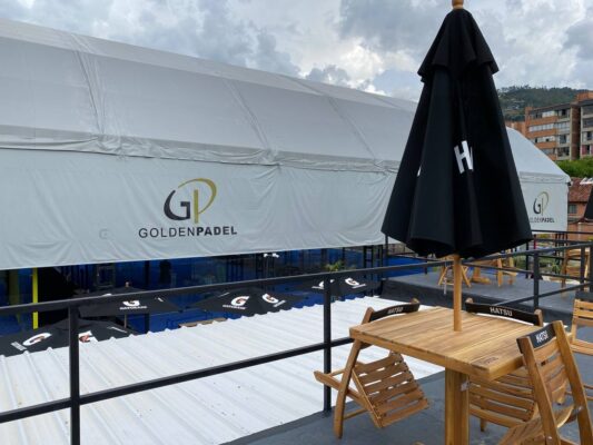 Barandas de metal en terraza del proyecto Golden Padel en Envigado, con mesas y sombrillas visibles