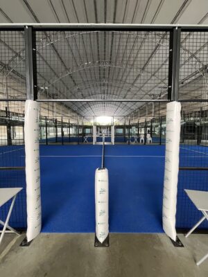 Entrada de cancha de pádel con barandas de metal y superficie azul, interior de un complejo deportivo