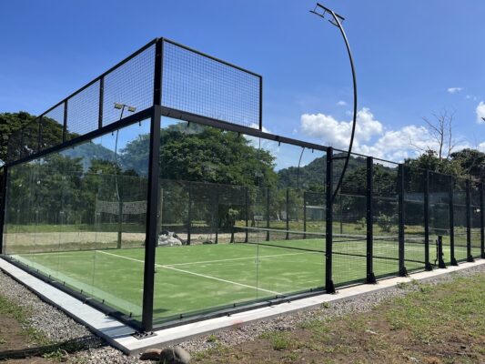 Canchas de pádel exteriores con estructura de metal y paneles de vidrio en un entorno natural