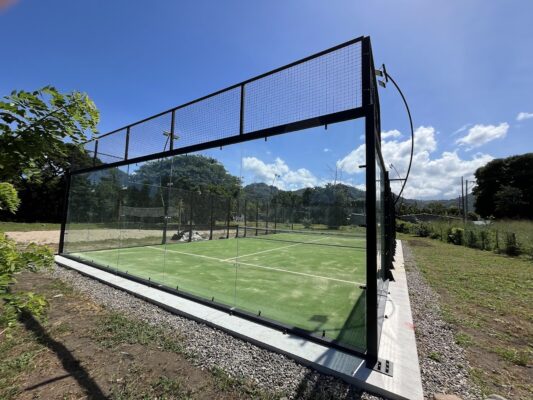 Canchas de pádel exteriores con estructura de metal y paneles de vidrio en un entorno natural